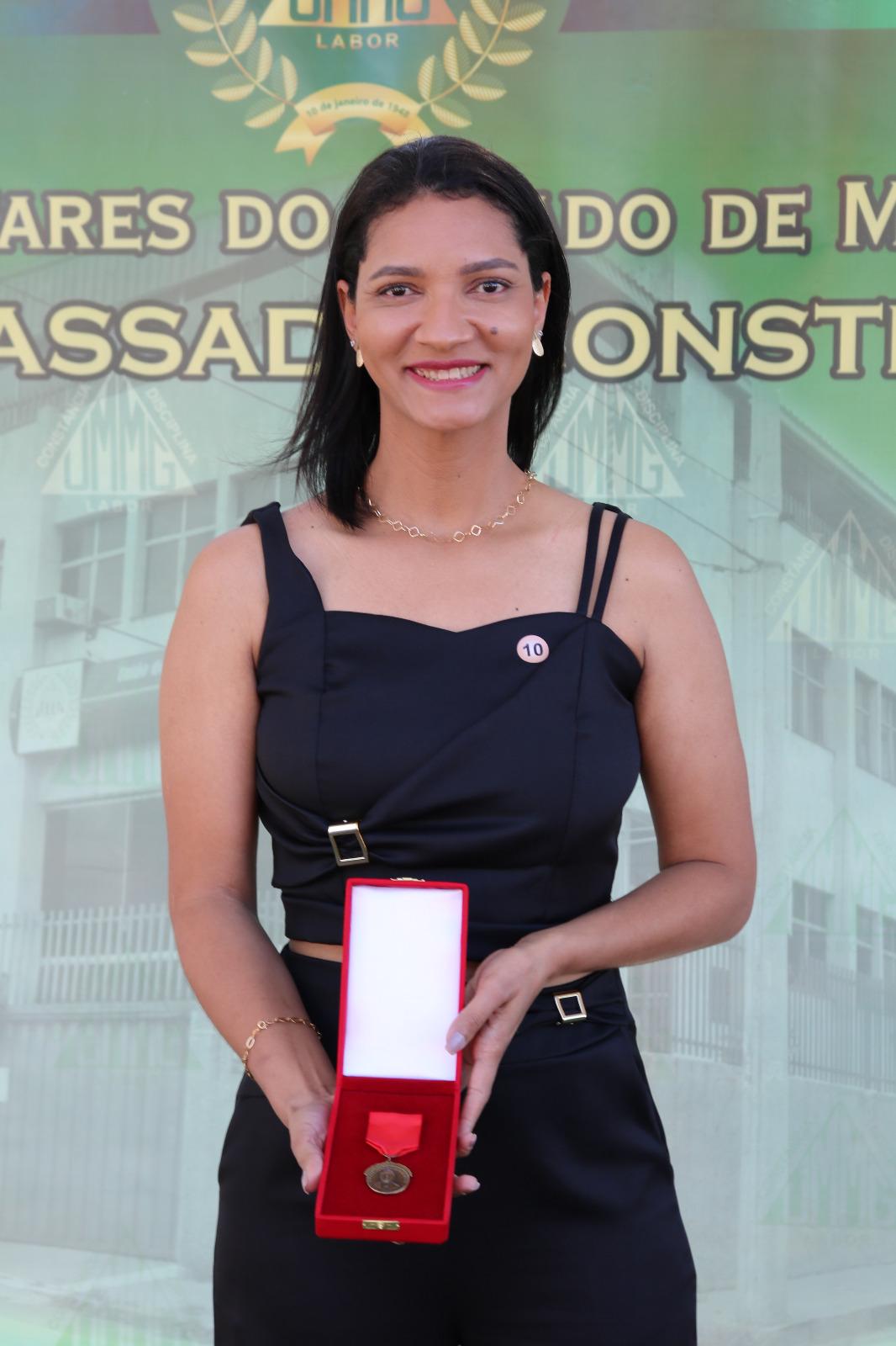 Tacielle Rufino, esposa do policial penal Reinaldo Neiva Ferreira, com a Medalha do Mérito Tenente-Coronel João Batista de Assis, concedida em reconhecimento ao ato de heroísmo do servidor. Foto: UMMG